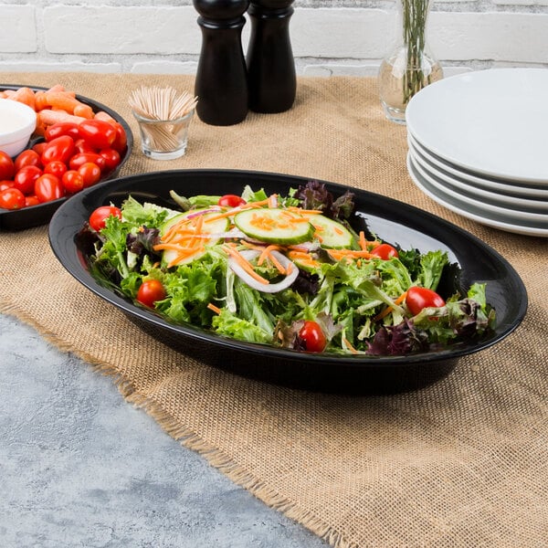 A salad in a Fineline black plastic oval catering bowl with tomatoes and carrots.