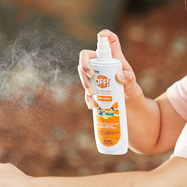 A person holding a white can of SC Johnson OFF! FamilyCare Unscented Insect Repellent spraying insect repellent.