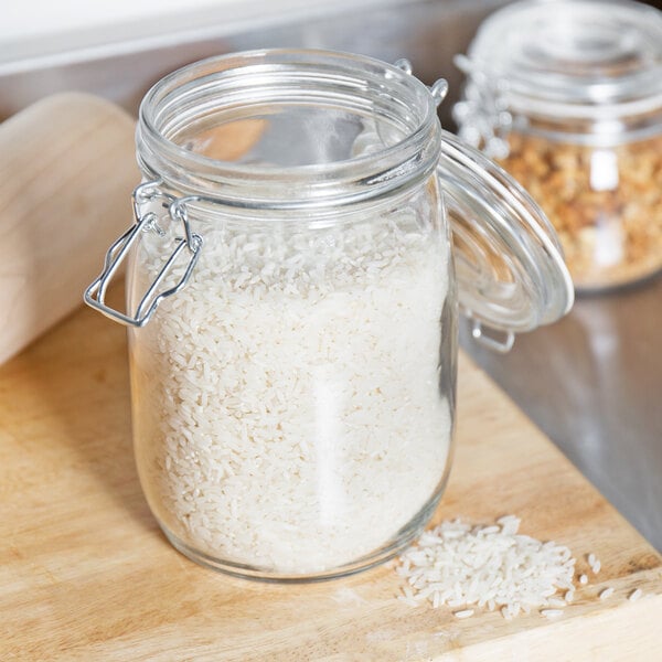 A Choice glass storage jar filled with white rice on a cutting board.