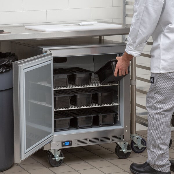 A man in a white coat opening a Beverage-Air undercounter freezer with a metal container.