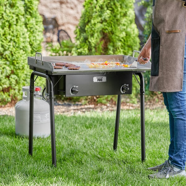 A woman cooking food on a Backyard Pro double burner outdoor range with a griddle plate.