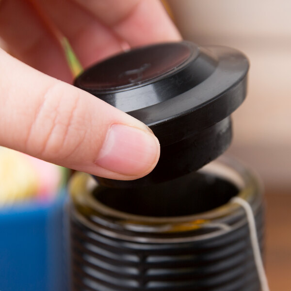 A person's hand opening a black round lid on a Libbey Hottle Server.