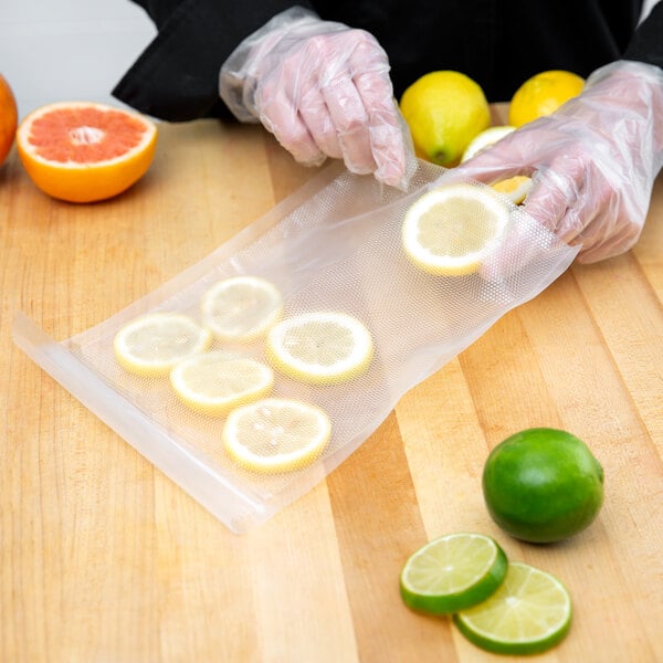 A person in gloves holding a VacPak-It Pint Size vacuum packaging bag with lemons and oranges.
