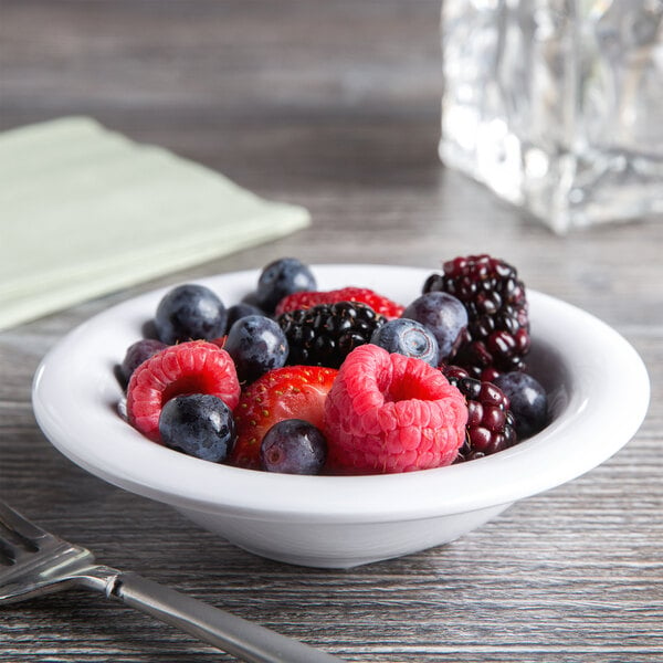 A Carlisle white melamine fruit bowl filled with berries on a table.