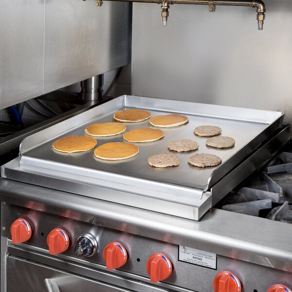 Pancakes cooking on a 24" x 27" Add-On 4 Burner Griddle Top on a gas stove.