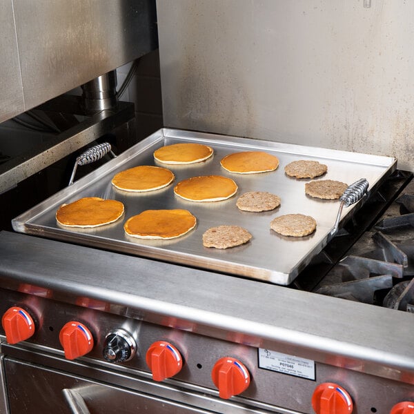 A pancake cooking on a Vigor portable steel griddle on a stove.