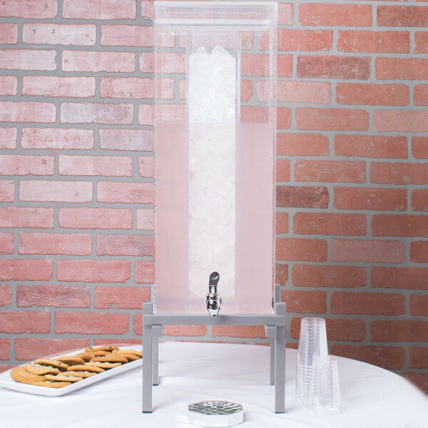 A Cal-Mil silver plastic beverage dispenser with ice in the top.