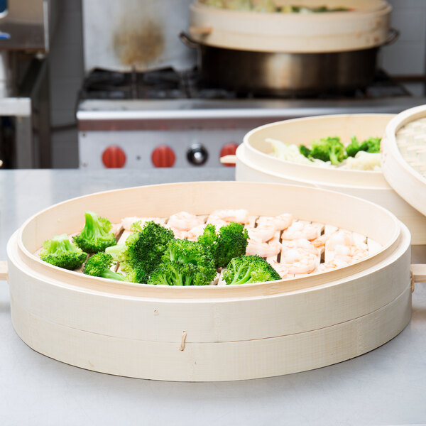 A group of Town bamboo steamers with bowls of food, including broccoli.