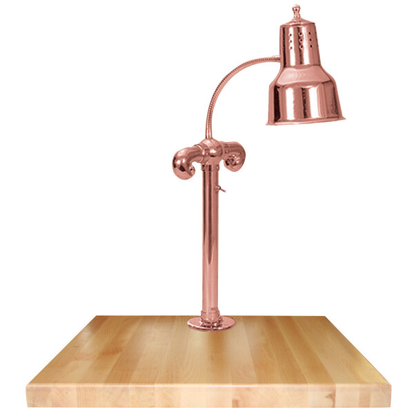 A Hanson Heat Lamps bright copper carving station lamp on a maple surface.