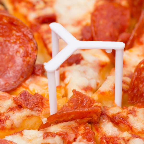 A white plastic Royal Paper pizza saver in the middle of a pizza.