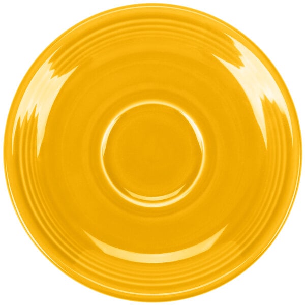 A yellow Fiesta saucer with a circular ring on a yellow surface.