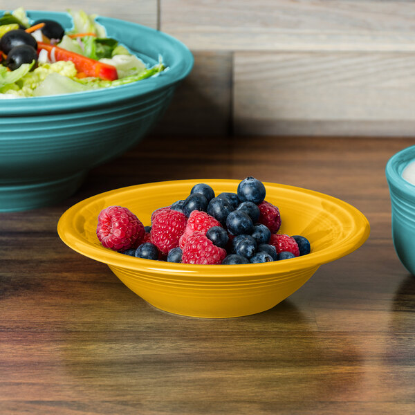 A Fiesta daffodil china bowl filled with fruit and salad on a table.