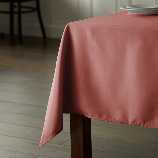 A table with a mauve rectangular Intedge tablecloth.