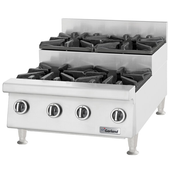 A stainless steel U.S. Range countertop with six black gas burners.