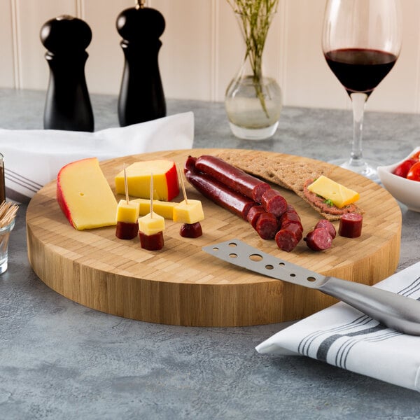 An American Metalcraft bamboo cutting board with sausages and cheese on a table.