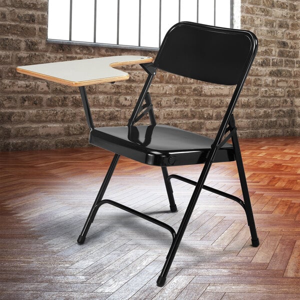 A black National Public Seating folding chair with a right gray tablet arm.