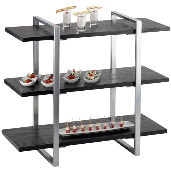 A black and silver three tier Cal-Mil metal frame riser with food on it.