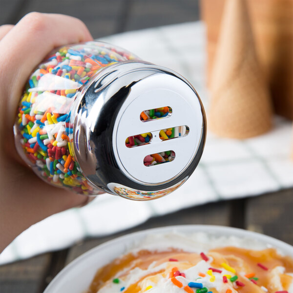A Tablecraft slotted shaker top on a glass jar filled with sprinkles.