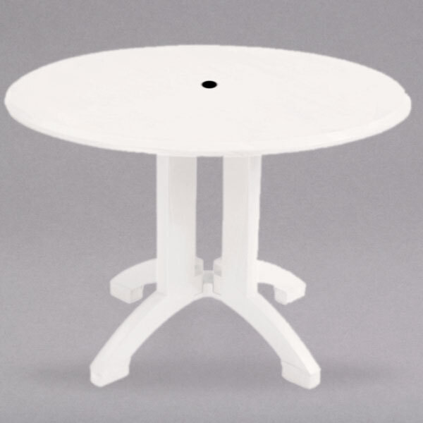 A white Grosfillex round outdoor table with an umbrella hole.