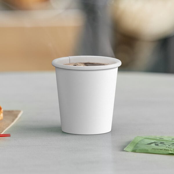 A white Choice paper hot cup filled with a drink on a table with a bag of food.