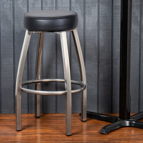 A Lancaster Table & Seating backless metal bar stool with a black vinyl seat.