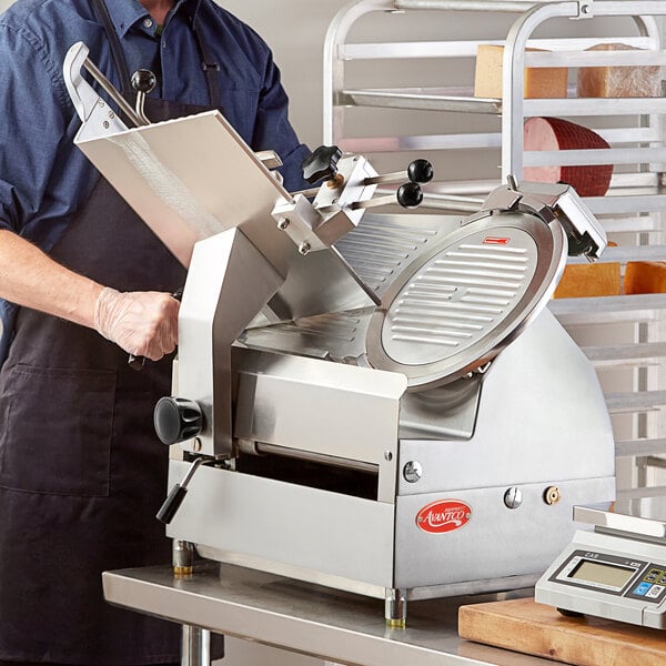 A man in a blue shirt and black apron using an Avantco meat slicer on a counter.