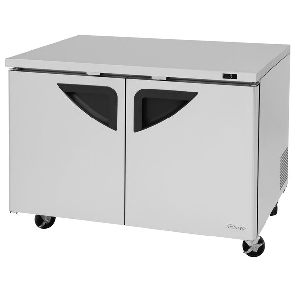 A stainless steel Turbo Air undercounter freezer with black handles.
