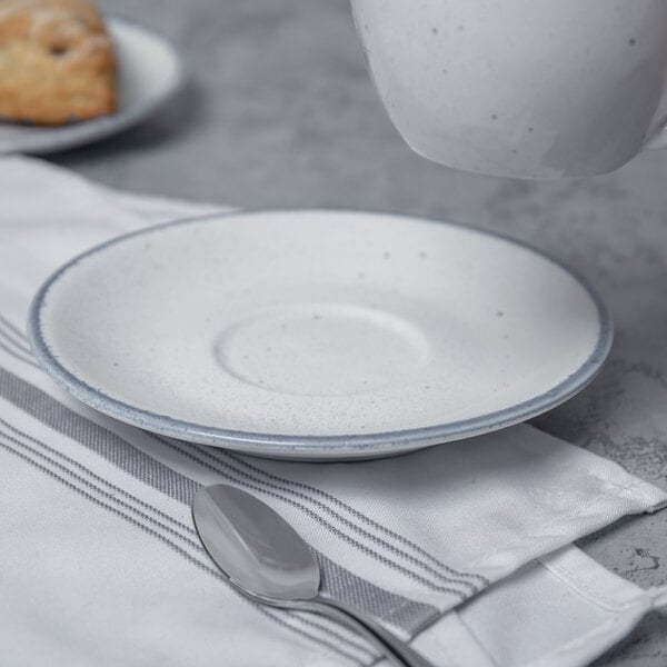 A 10 Strawberry Street Arctic Blue saucer with a plate and spoon on a table.