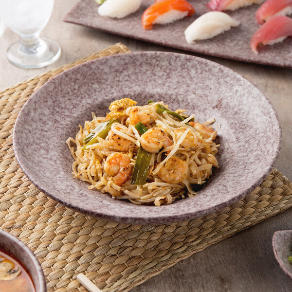 A Biseki stoneware pasta bowl filled with asian noodles and shrimp on a table.