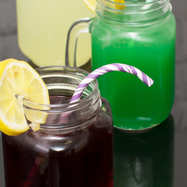A glass jar with a Creative Converting amethyst paper straw in it next to a glass of lemonade.