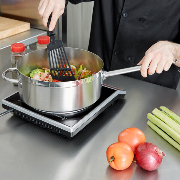A chef using a Vollrath Centurion saute pan to cook vegetables.