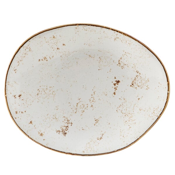 A white oval Tuxton China plate with brown specks on the rim.