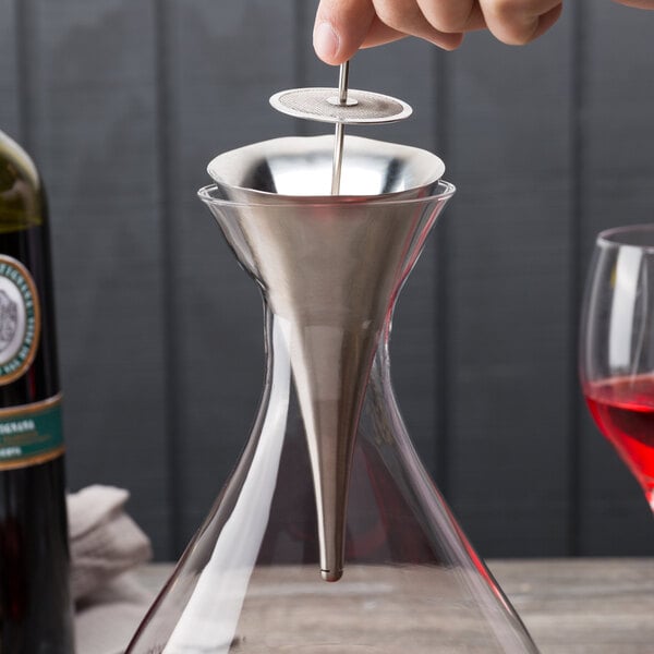 A person using a Franmara stainless steel funnel to pour wine into a decanter.
