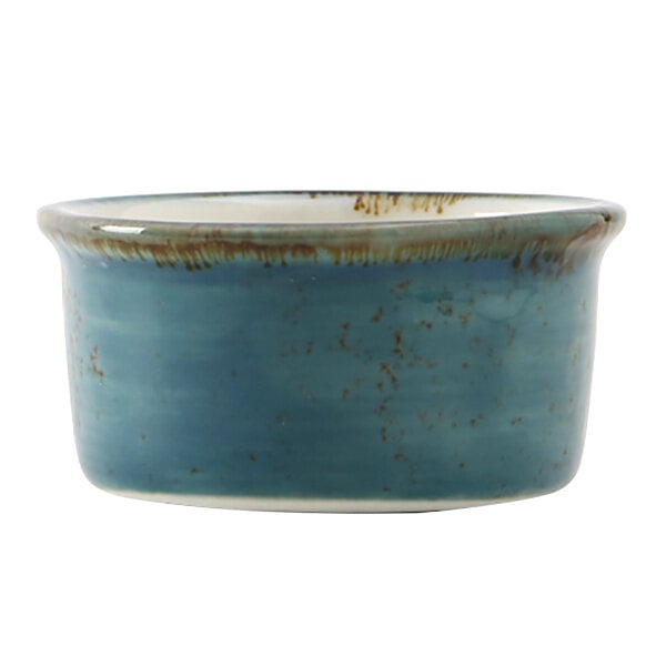 A blue ceramic Tuxton ramekin with brown specks on the rim.