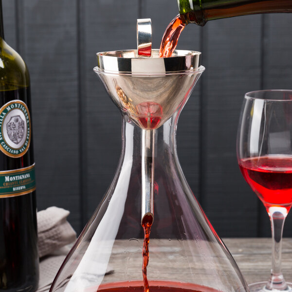 A Franmara Classic silver metal decanter funnel being used to pour red wine into a glass decanter.