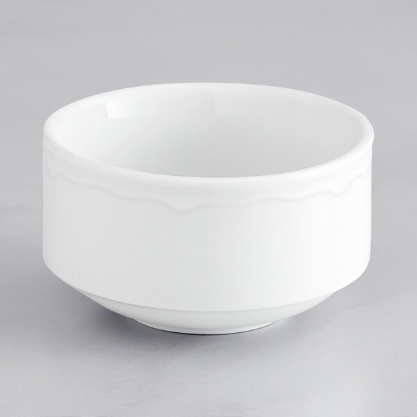 A Tuxton Charleston bright white scalloped edge bowl on a gray surface.
