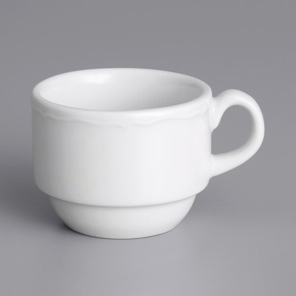 A white Tuxton espresso cup with a scalloped edge and handle.
