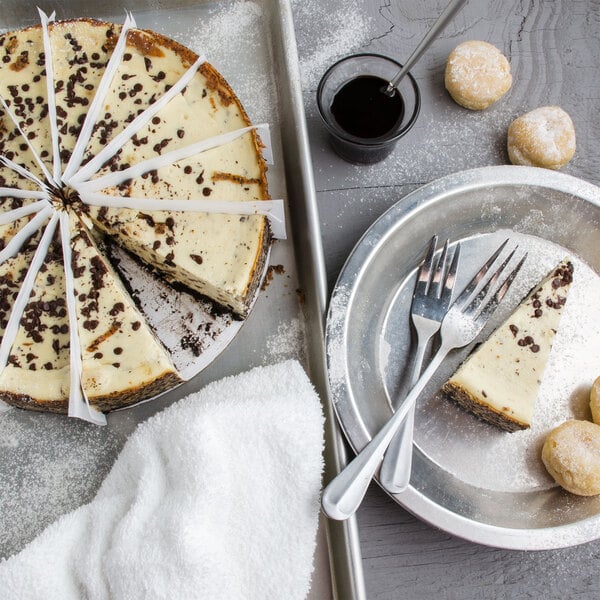 A Pellman chocolate chip cheesecake with a slice cut out on a plate with a fork and knife.