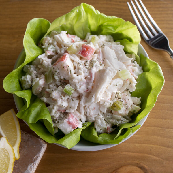 A bowl of Spring Glen Fresh Foods Seafood Salad with a fork and lemon.