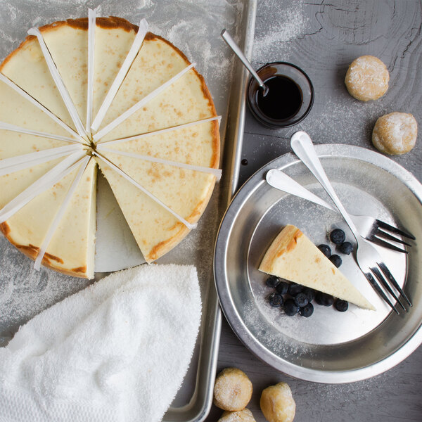 A Pellman plain cheesecake with a cut piece on a tray with a fork and spoon.