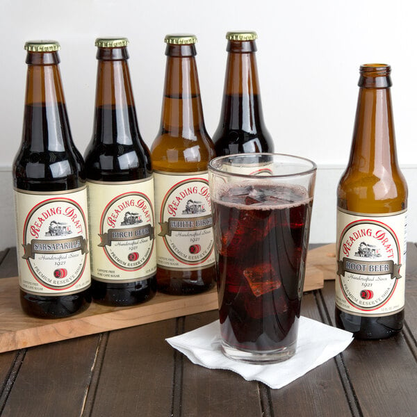 A group of Reading Soda Works Dutch Sampler bottles with a glass of dark liquid.