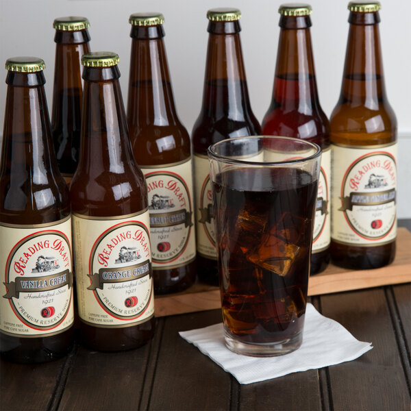 A group of Reading Soda Works brown bottles with a glass of liquid.