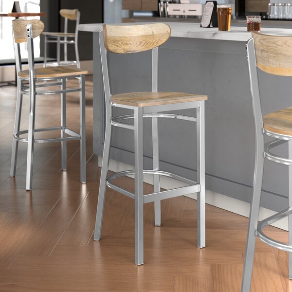 Lancaster Table & Seating Boomerang bar stools with driftwood seats and backs at a table in a pub interior.
