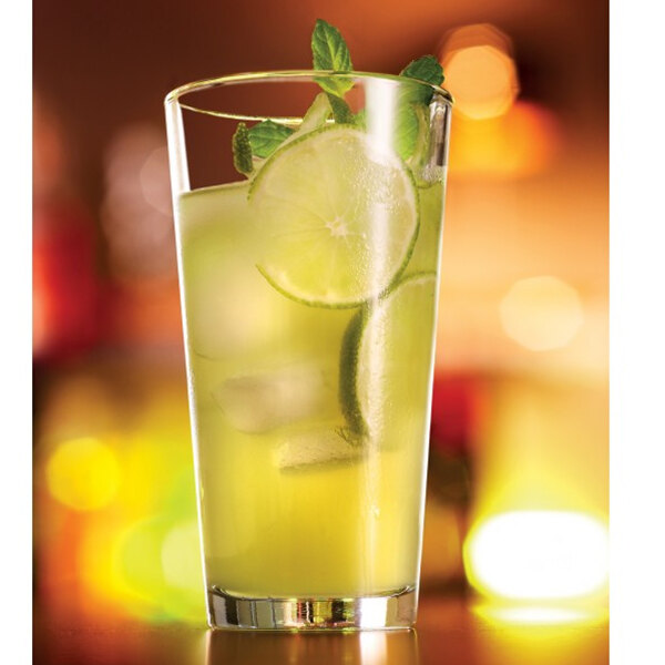 An Arcoroc beverage glass filled with lemonade, lime slices, and mint leaves on a white background.