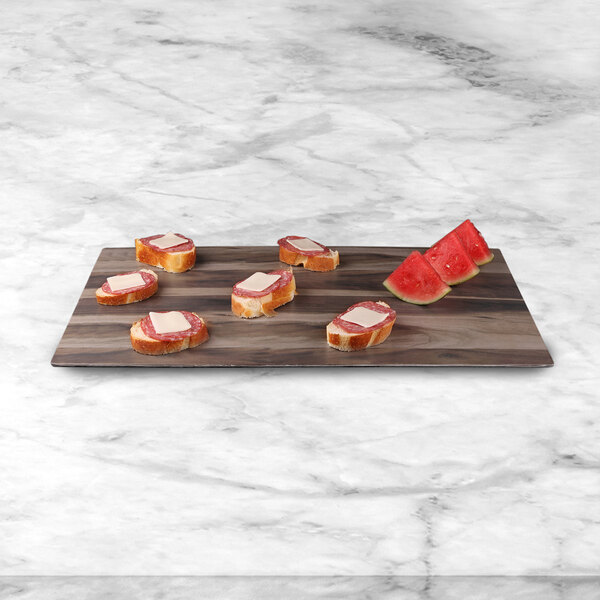 A faux hickory wood melamine serving board with slices of bread and watermelon on it.