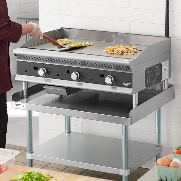A woman using a Vollrath Cayenne countertop gas griddle to cook food.