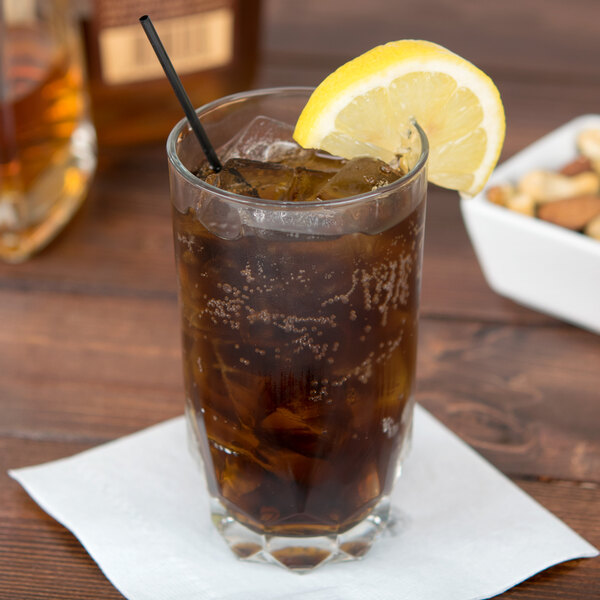 An Arcoroc highball glass of iced tea with a lemon wedge and a straw.