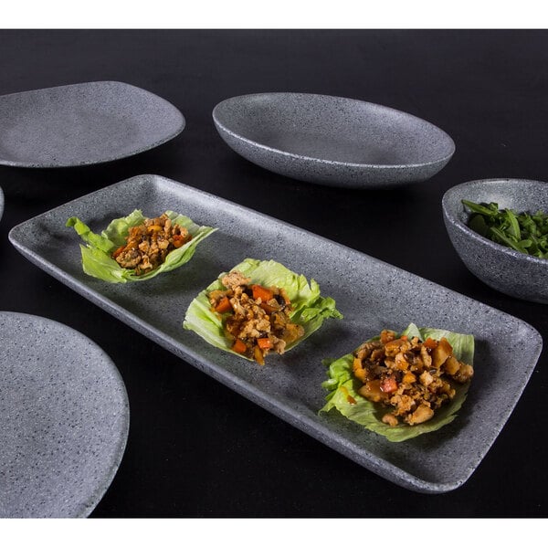 A set of six Elite Global Solutions rectangular granite stone melamine plates with food on a table.