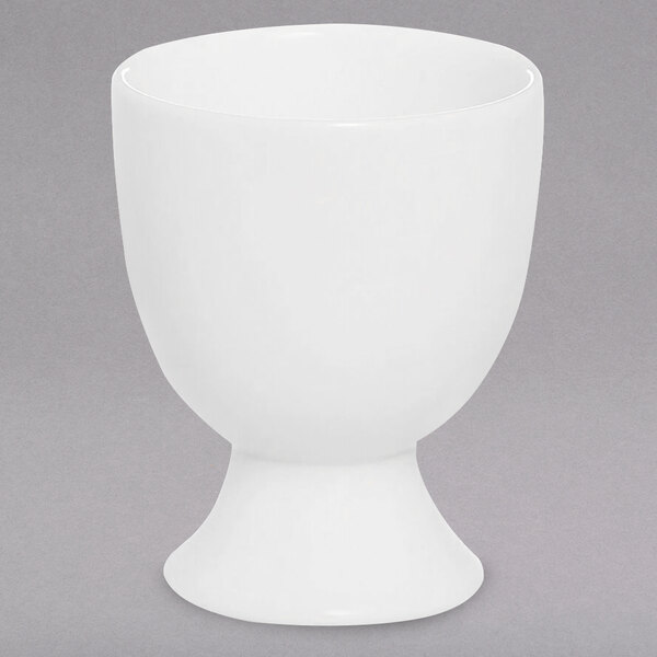 A Chef & Sommelier white bone china egg cup with a base on a gray surface.