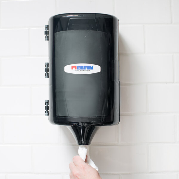 A hand pulling a grey towel from a black Merfin mini center pull towel dispenser.